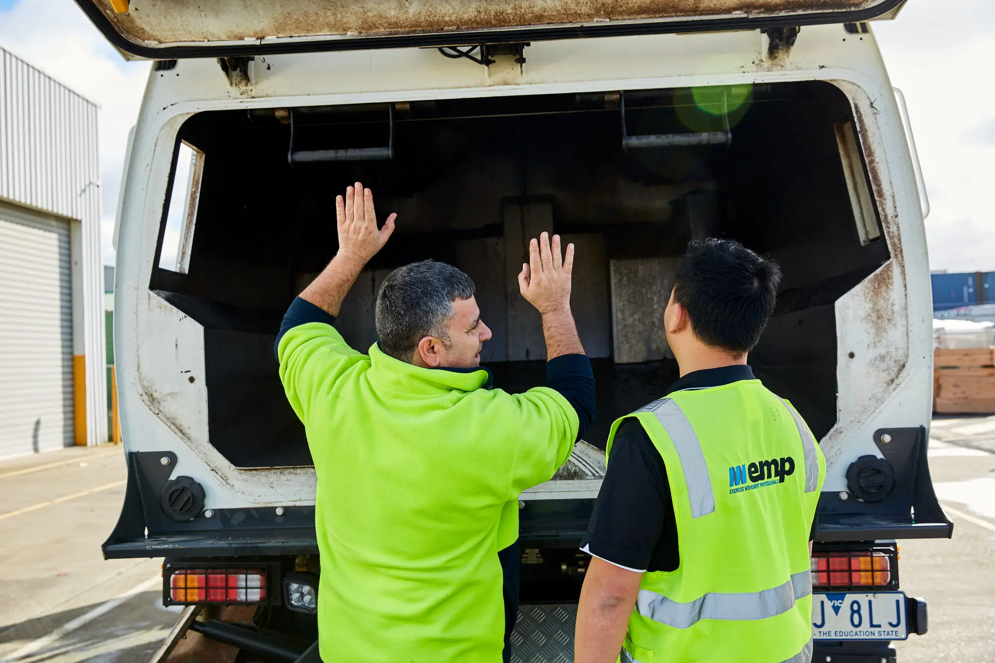 Two EMP Onsite clinicians in high-visibility vests reviewing the load area of a work vehicle.