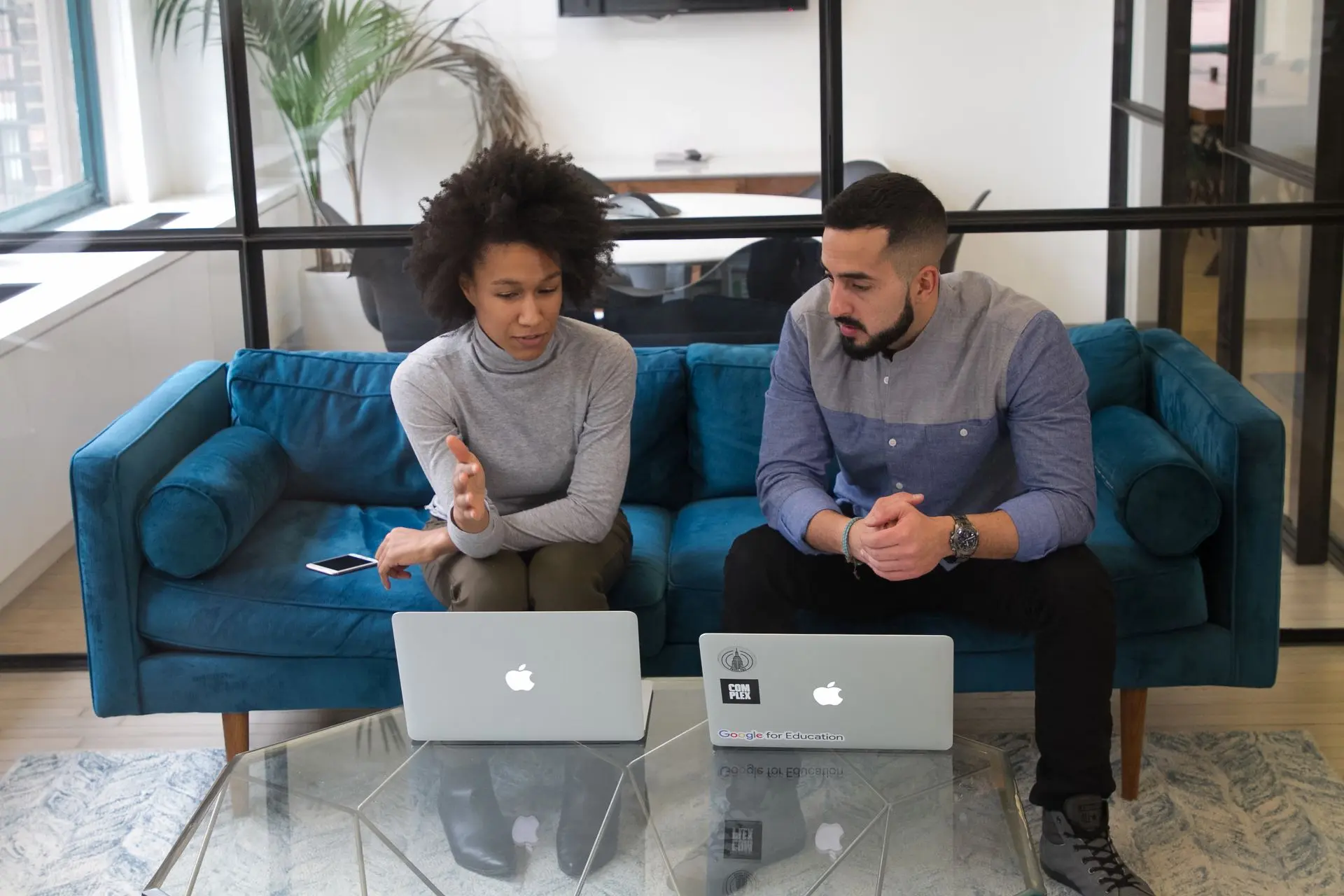 Two office workers having a conversation while seated on a sofa