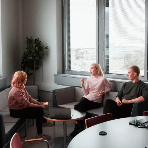 Three office workers sitting in an office having a conversation