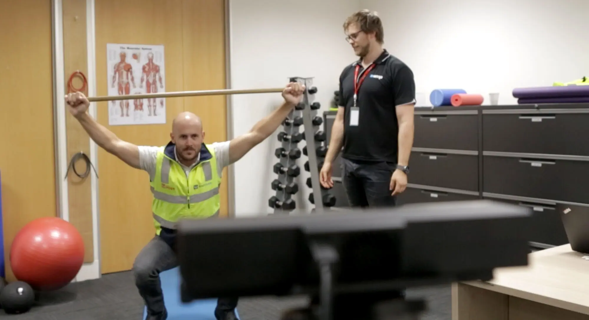 An EMP Onsite clinician observing a worker performing an overhead movement while wearing motion sensors.