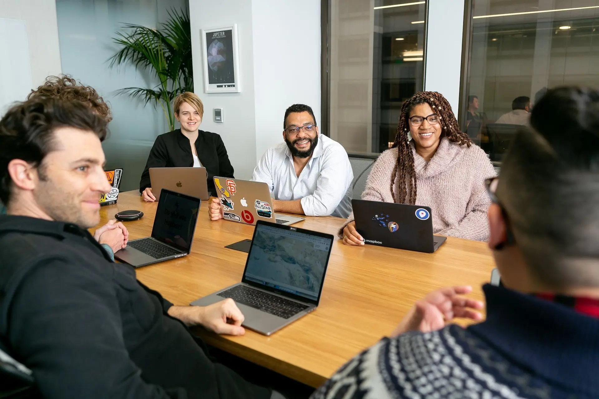 Several office workers with laptops sitting around a desk